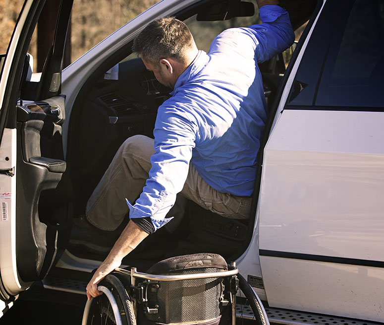 Man in a wheelchair getting into a car