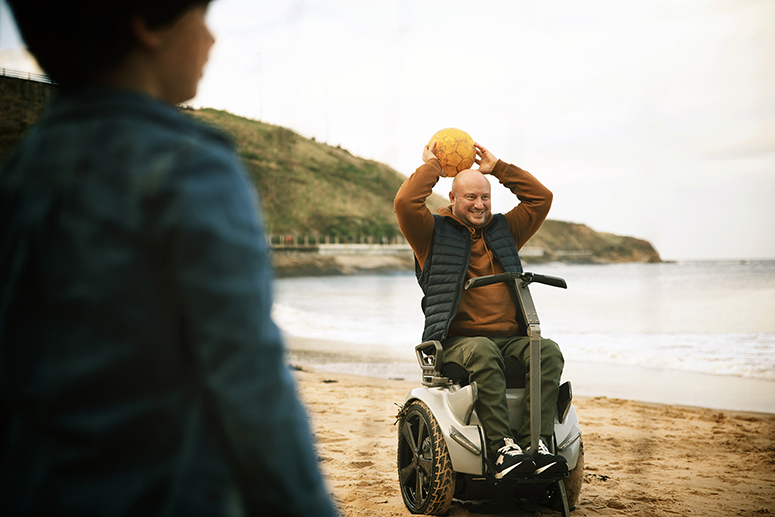 Man in wheelchair playing basket ball on a beach